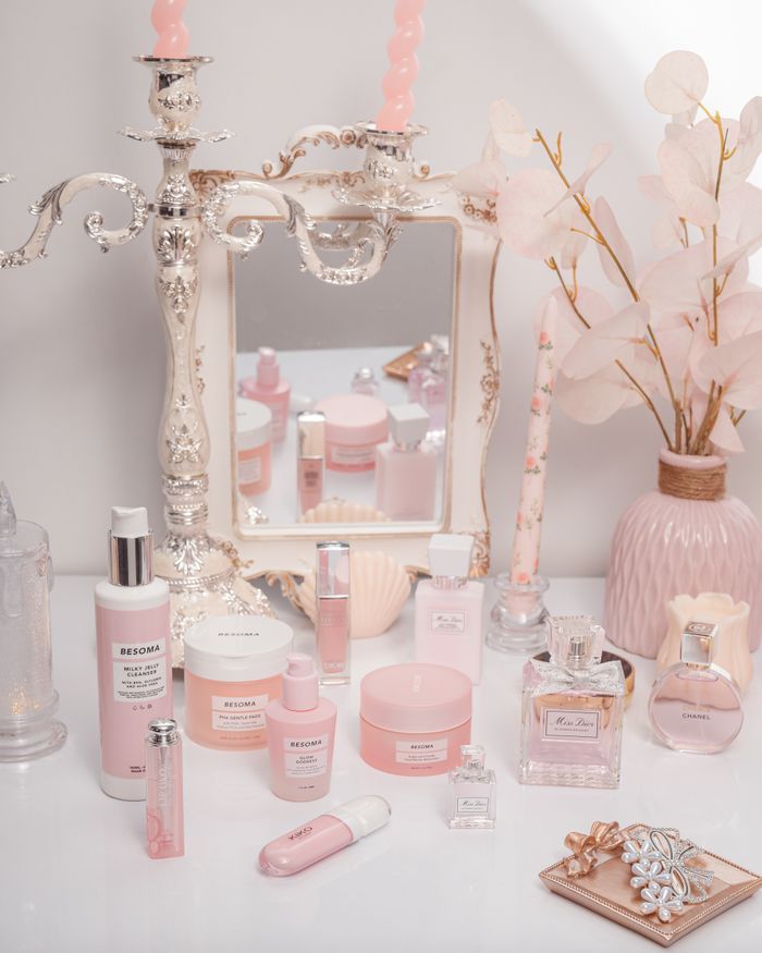 Charming arrangement of pink cosmetics with candles and a mirror, exuding elegance.