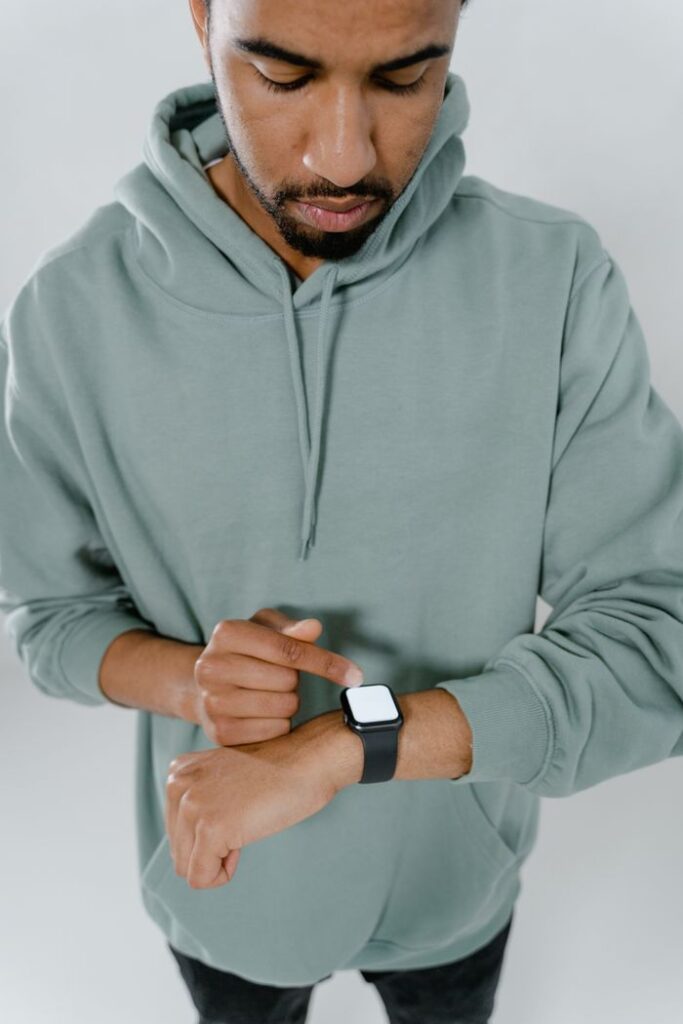 The Art of Drawing Readers In: Your attractive post title goes here Man wearing a green hoodie checking time on a smartwatch, emphasizing modern technology.